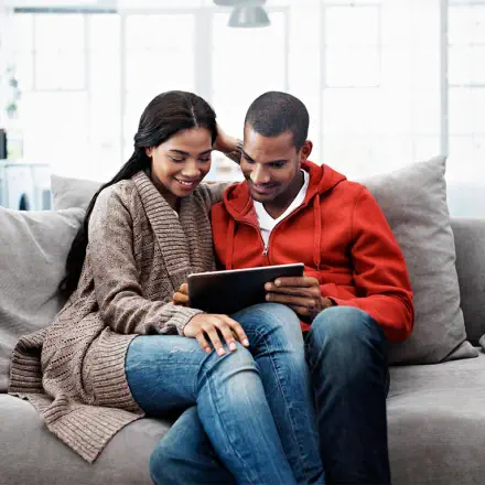 couple on the couch reviewing their finances on an ipad