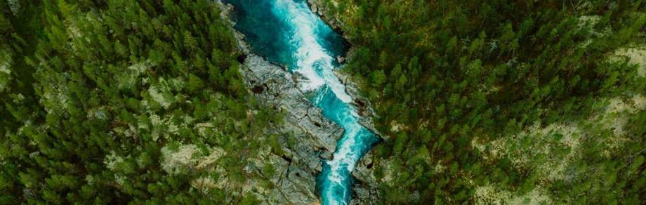 Scenic aerial view of the mountain landscape with a forest and the crystal blue river.
